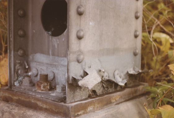 FIGURE 2 Base of an aluminum column showing exfoliation corrosion and partially blocked, semi-circular drainage holes.