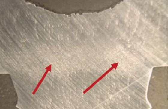 FIGURE 5 Longitudinal section of screw ground polished and etched revealed grain flow (red arrows).