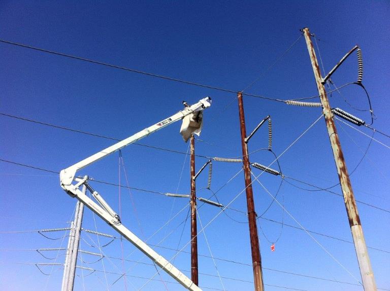 Workers perform surface preparation on a de-energized 138-kV pole prior to the application of an epoxy coating system. Photo courtesy of Cris Conner.