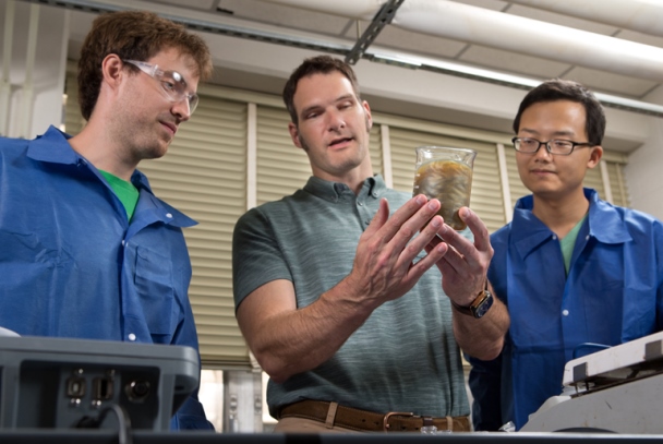 Jaime Grunlan, center, discusses the behavior of a clay solution to Texas A&M doctoral students Ryan Smith, left, and Yixuan Song. These clay solutions are used with Sandia to produce nanocomposite thin films and coatings. Photo courtesy of Texas A&M University.