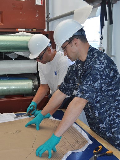 Engineers prepare laminate material for a composite patch repair on the USS Cape St. George (CG 71). Photo courtesy of Daniel Hart, Naval Surface Warfare Center, Carderock Division.