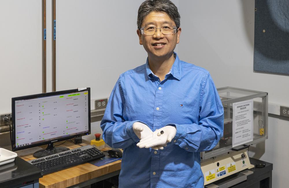 ORNL’s Jun Qu shows stainless-steel disks before (silver) and after (black) coating with carbon nanotubes that provide superlubricity. Photo by Carlos Jones/ORNL, U.S. Department of Energy.