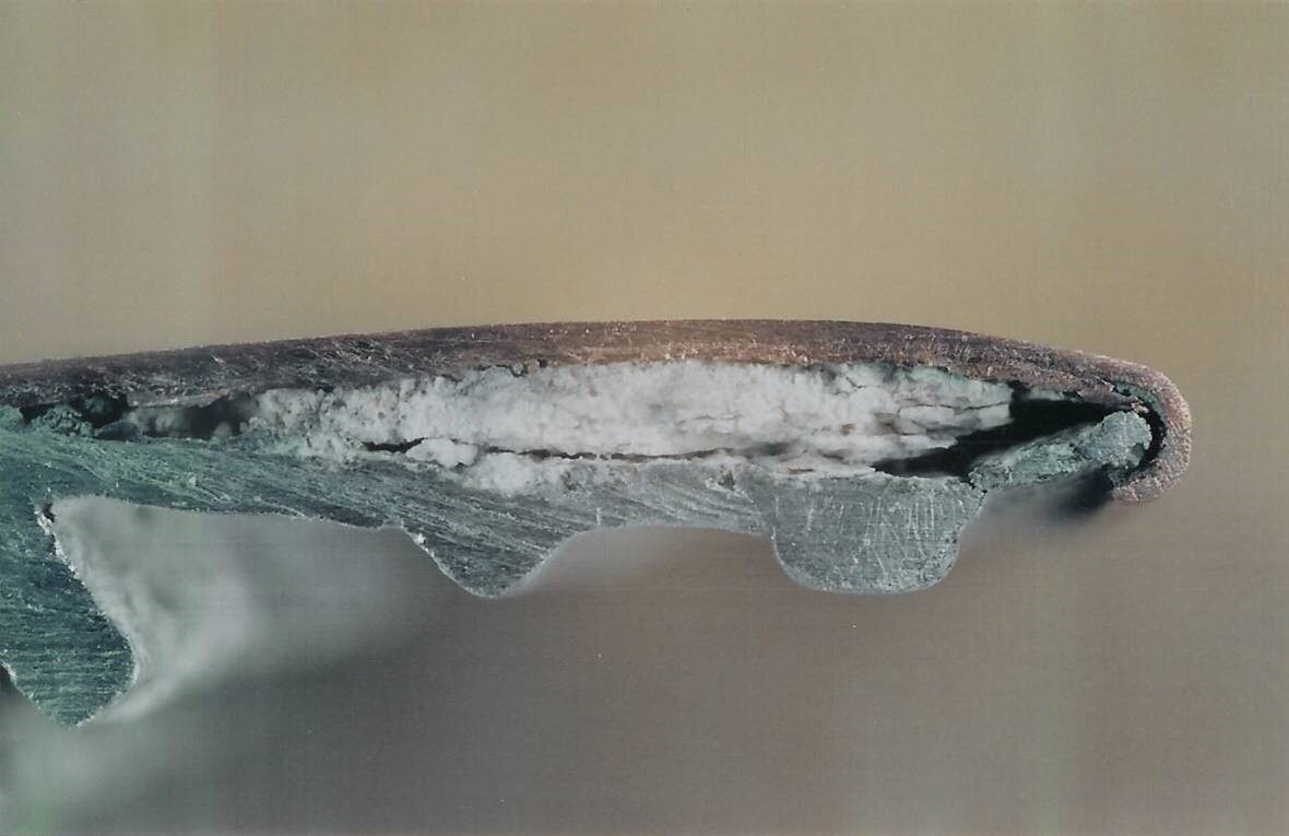 FIGURE 3 Close-up view of cross-section through the dress cap showing copper cladding and white corrosion products formed on the underlying aluminum.