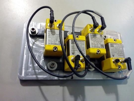 Four ultrasound sensors (Sensorlink Swarm) are placed on the opposite side of the steel plate recording ultrasound data as the holes are drilled stepwise.