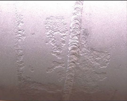 FIGURE 4 External corrosion under solid film-backed, CP-shielding girth weld coating, but no corrosion under the mainline FBE coating.