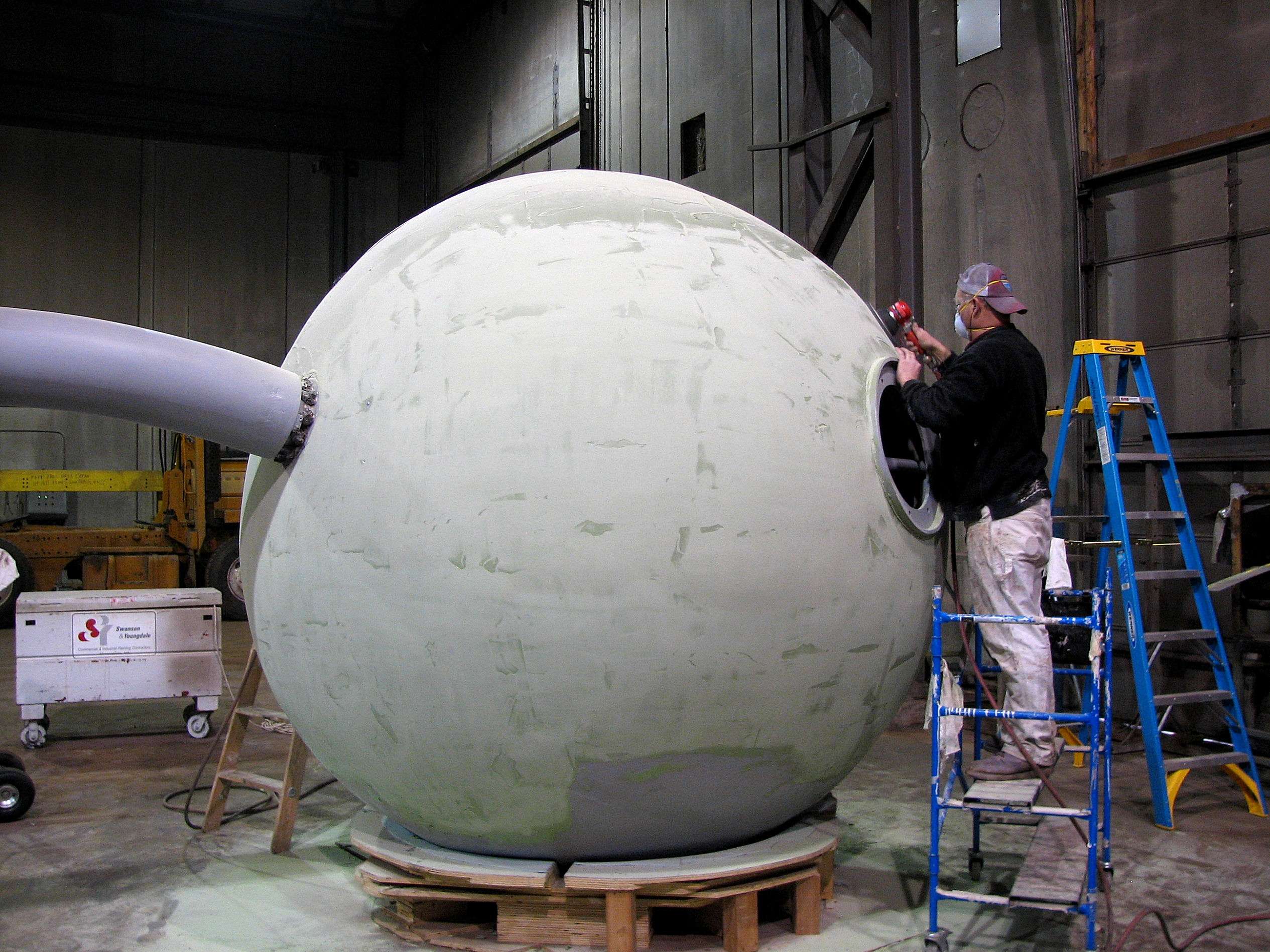 Figure 2: A worker applies and finishes the fairing compound. Once the first epoxy coats were applied, the process of reshaping the sculpture began. Several coats of fairing compound were used to recreate the original “cherry” shape.