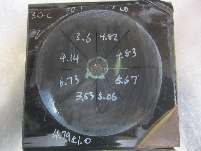 To determine cathodic disbondment using TM0115-2015, four radial cuts using a sharp blade are made through the drilled holiday in the sample. A rigid knife is used to lift and remove the disbonded coating at the drilled holiday until no more disbondment can be detected. The disbonded area is calculated using the difference between the average disbondment diameter and the drilled holiday diameter. Photo courtesy of Dennis Wong.